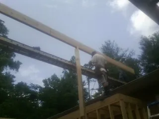 Carpenter setting a ridge beam over a new addition frame — Ice Dam Removal by Roofing Brothers in Grayson