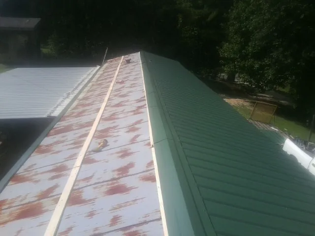 Old rusted panels beside newly installed green metal roofing — Wind Damage Roof Repair by Roofing Brothers in Grayson