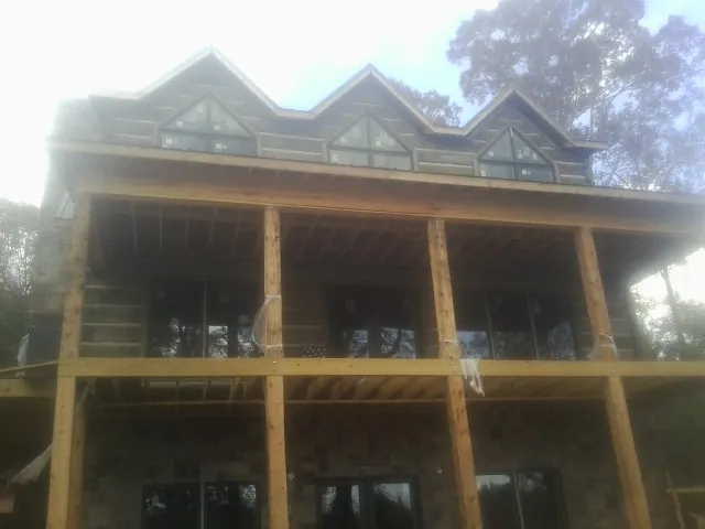 Dormers and porch framing on a large log home under construction — Roof Coating work by our crew in Grayson