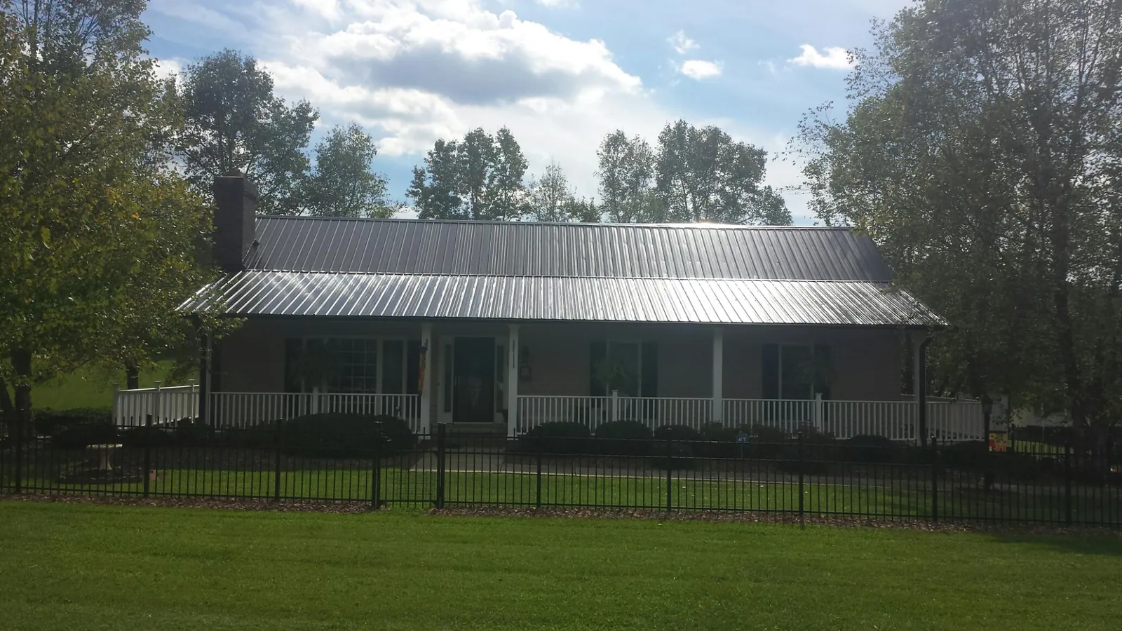 Gray metal roof on a brick ranch with a full width front porch — Gutter Guard Installation work by our crew in Grayson