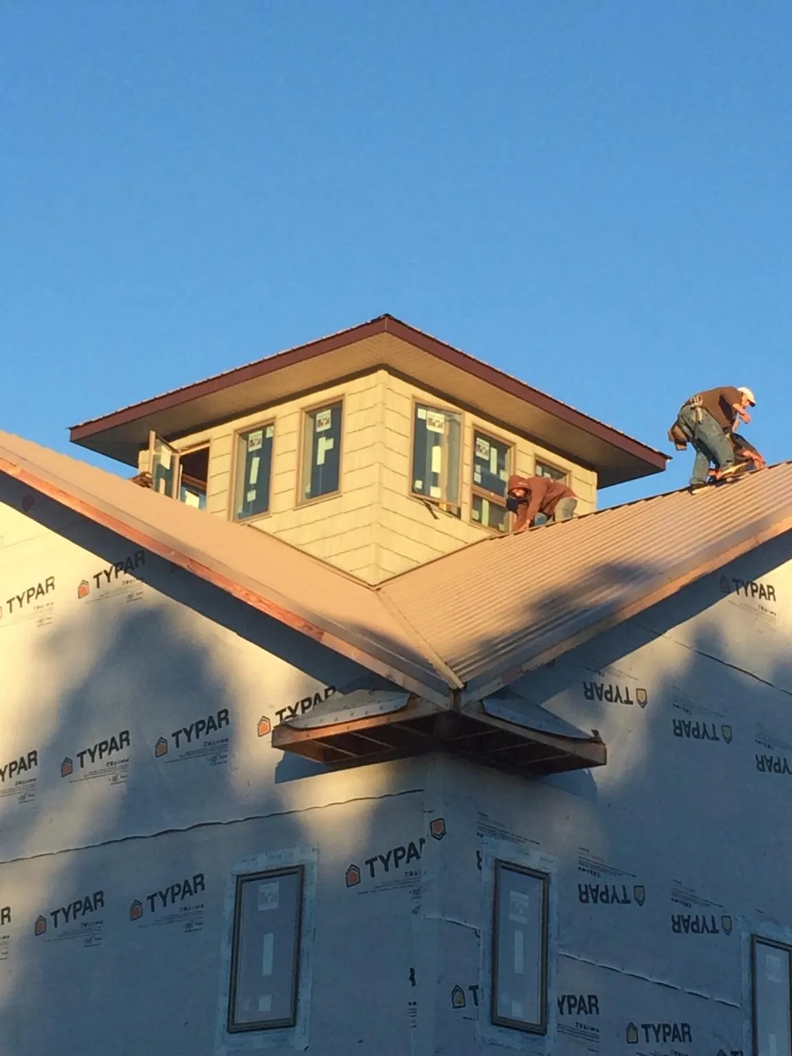 Roofers working around a rooftop cupola on a new metal roof at sunset — Roof Waterproofing in Grayson by Roofing Brothers